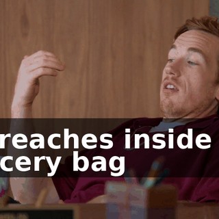 He reaches inside the grocery bag
